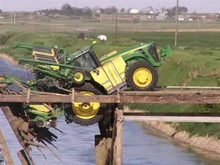 A John Deere tractor stuck falling through a bridge